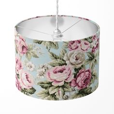 a lamp shade with pink and white flowers on blue fabric, hanging from a metal hook