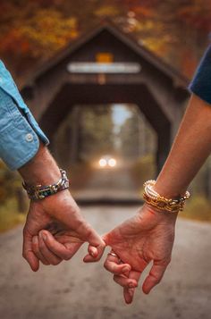 two people holding hands while walking down a road