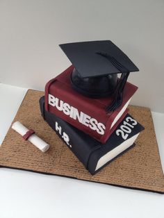 a graduation cake made to look like books with a mortar and diploma cap on top