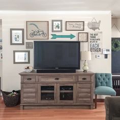 a flat screen tv sitting on top of a wooden cabinet in a living room next to a blue chair