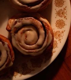 three cinnamon rolls on a plate with icing