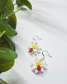 two ladybug earrings sitting on top of a plant