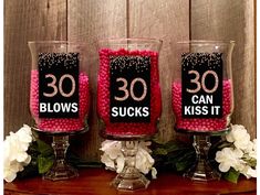 three wine glasses decorated with pink and black candies are sitting on a wooden table