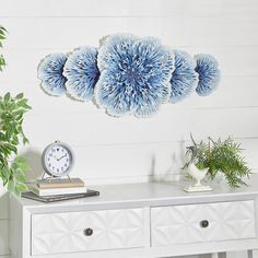 a white table with three blue flowers on it and a clock hanging from the wall