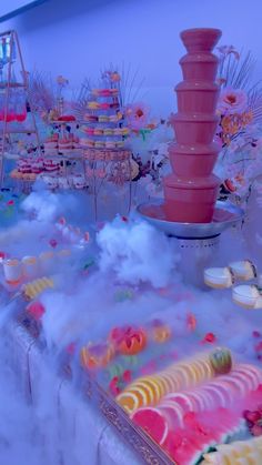 there is a pink fountain in the middle of this table filled with cakes and desserts