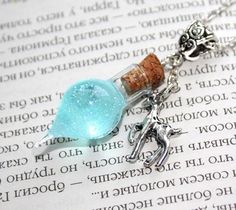 a necklace with a glass bottle and anchor charm on top of an open page of paper