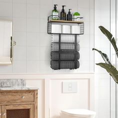 a white toilet sitting next to a wooden cabinet in a bathroom under a mirror and towel rack