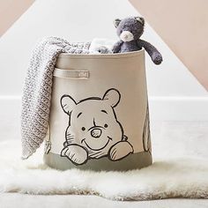 a teddy bear sitting inside of a canvas storage container with a blanket on top of it