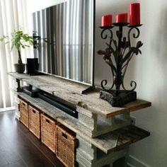 a large mirror sitting on top of a wooden shelf next to a vase with red candles