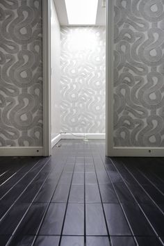 an open door leading into a room with tile flooring and wall paper on the walls