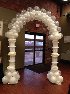 an arch made out of balloons in the middle of a room with wooden flooring