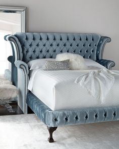 a bed with a blue headboard sitting in a bedroom next to a large mirror