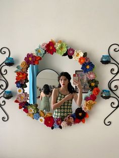 a woman taking a selfie in front of a mirror with flowers on the wall