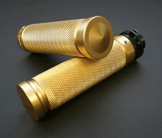 two gold - plated metal objects on a black surface, one with a round top