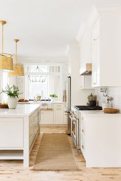 a kitchen with white cabinets and wood flooring is pictured in this image, there are plants on the counter