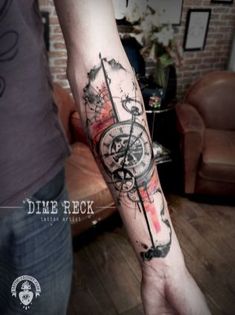 a man's arm with a compass and watercolors tattoo on the forearm