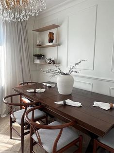 a dining room table with chairs and a vase on it