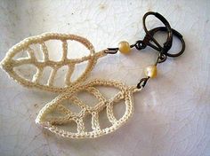 three crocheted earrings with beads hanging from them on a piece of cloth covered surface