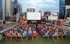 rows of lawn chairs sitting on top of a roof in front of city skylines