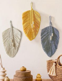 three different color fan shaped wall hangings on a wall next to a basket and vase