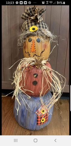 a scarecrow made out of pumpkins sitting on top of a wooden floor next to a wall