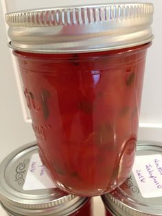 two jars filled with red liquid sitting on top of each other