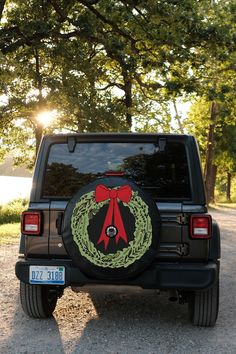 a black jeep with a wreath on it's back window and the sun shining in the background