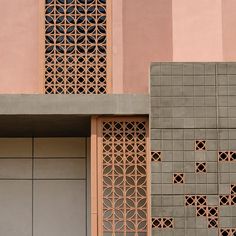 a clock on the side of a building next to a wall with geometric designs and windows