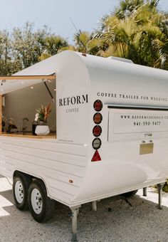 a small white trailer parked next to a palm tree