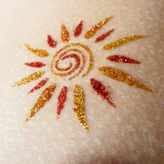 a close up of a person's chest with gold glitter on it and a sun design