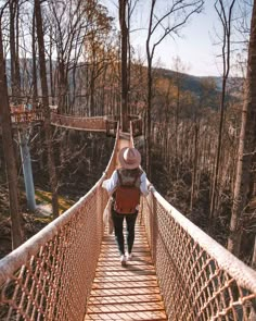 a person walking across a suspension bridge in the woods