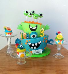 a monster themed birthday cake and cupcakes on a table