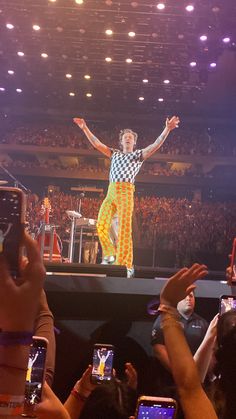 a man standing on top of a stage with his arms in the air while people take pictures