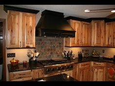 a kitchen with wooden cabinets and black counter tops, an oven hood over the stove