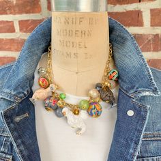 a mannequin wearing a blue jean jacket and a necklace with charms on it