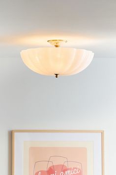 a painting hangs on the wall next to a framed art piece and a light fixture