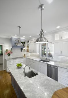 a large kitchen with white cabinets and marble counter tops, along with an island in the middle