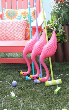 two pink flamingos standing next to each other in the grass