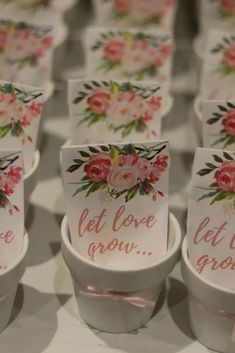 there are many cups that have flowers on them with cards attached to the top one