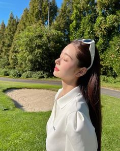 a woman with long hair standing in the grass and looking up at something behind her