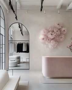 a pink bath tub sitting in front of a mirror next to a white couch and flower vase