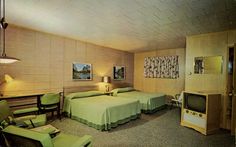 a motel room with two beds and green chairs