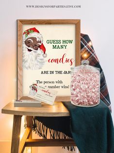 a wooden table topped with a glass jar filled with candy next to a christmas sign