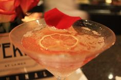 a close up of a drink in a wine glass with a red flower on top