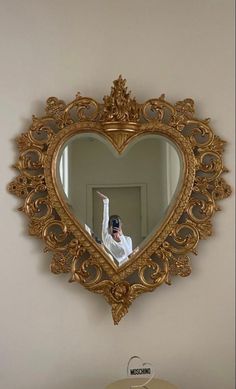 a man taking a selfie in front of a heart shaped mirror on the wall