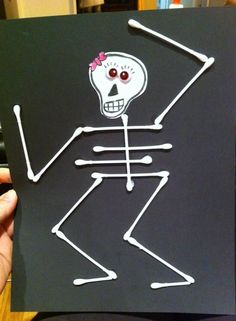 a hand holding up a piece of paper with a skeleton drawn on it's side