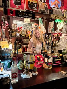 a woman standing behind a bar filled with liquor bottles