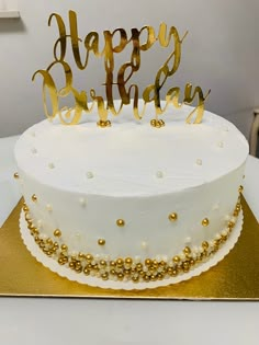 a white and gold birthday cake with the words happy birthday on it's top