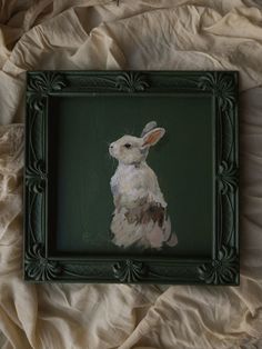 a painting of a white rabbit in a green frame