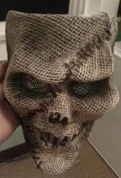 someone is holding up a burlap skull mask